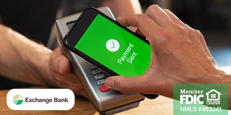 Man holding phone against portable point of sale system with screen that is green and says Payment Sent on phone