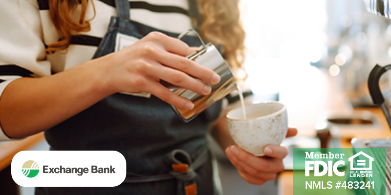 Image shows young barista pouring liquid into ceramic mug