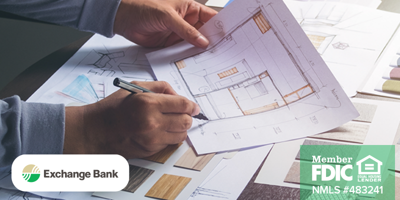 Image shows person writing on blueprint on table with other building documents