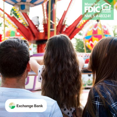 Image shows two adults and a child looking over a barrier at a fair ride