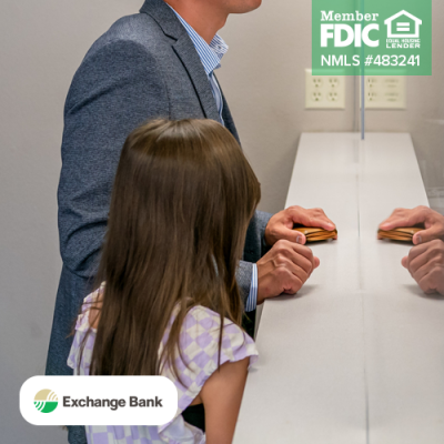 Father at bank counter with daughter standing next to him