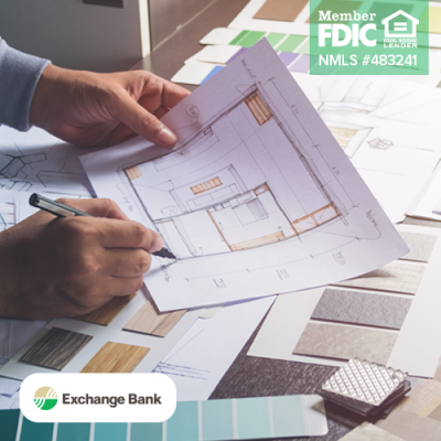 Image shows person writing on blueprint on table with other building documents