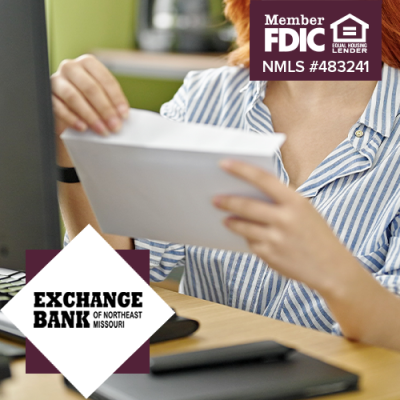 Woman opening envelope in front of her computer at her desk